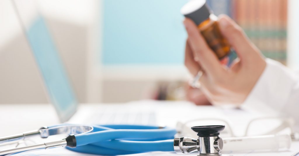 doctor working on a laptop testing medicine