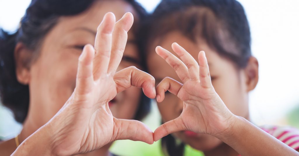 Picture of two people making a heart with their hands.